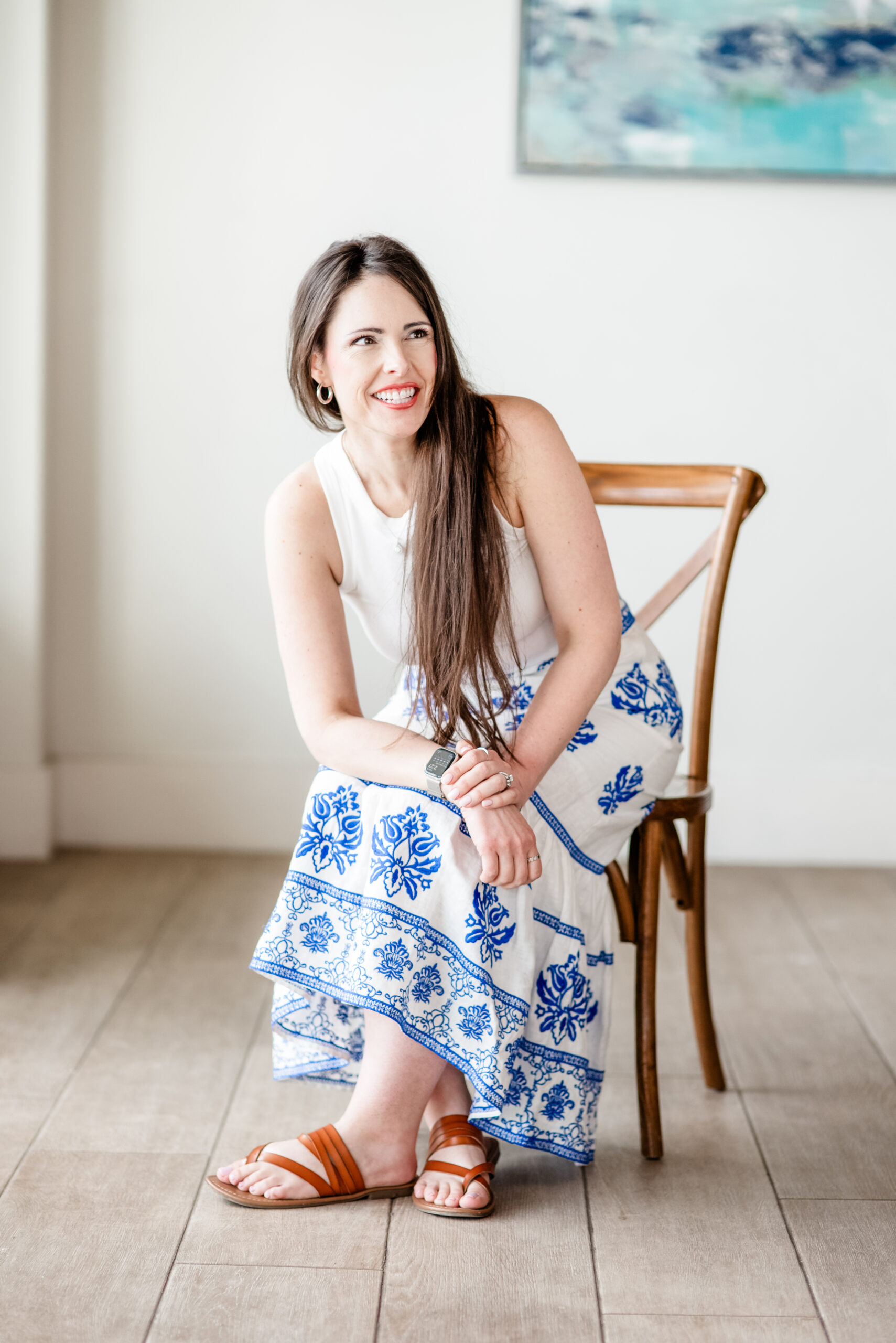 Angela sitting in a wooden chair, smiling over her shoulder